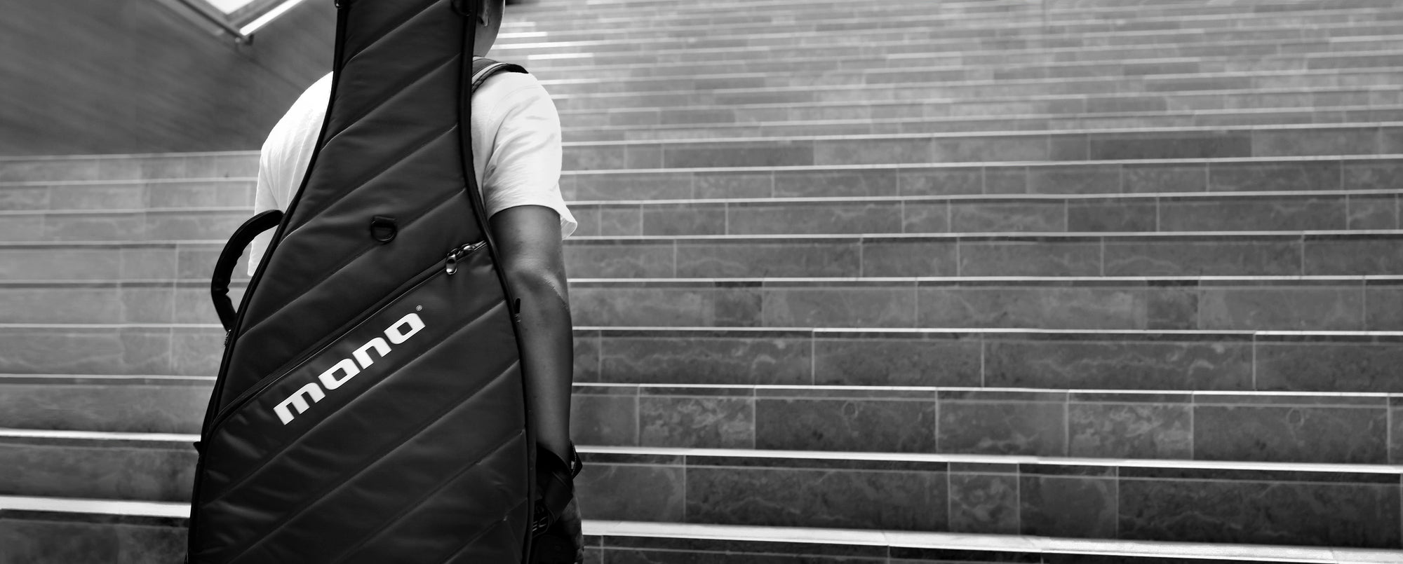 A man going up the stairs and carrying a MONO M80 Vertigo case